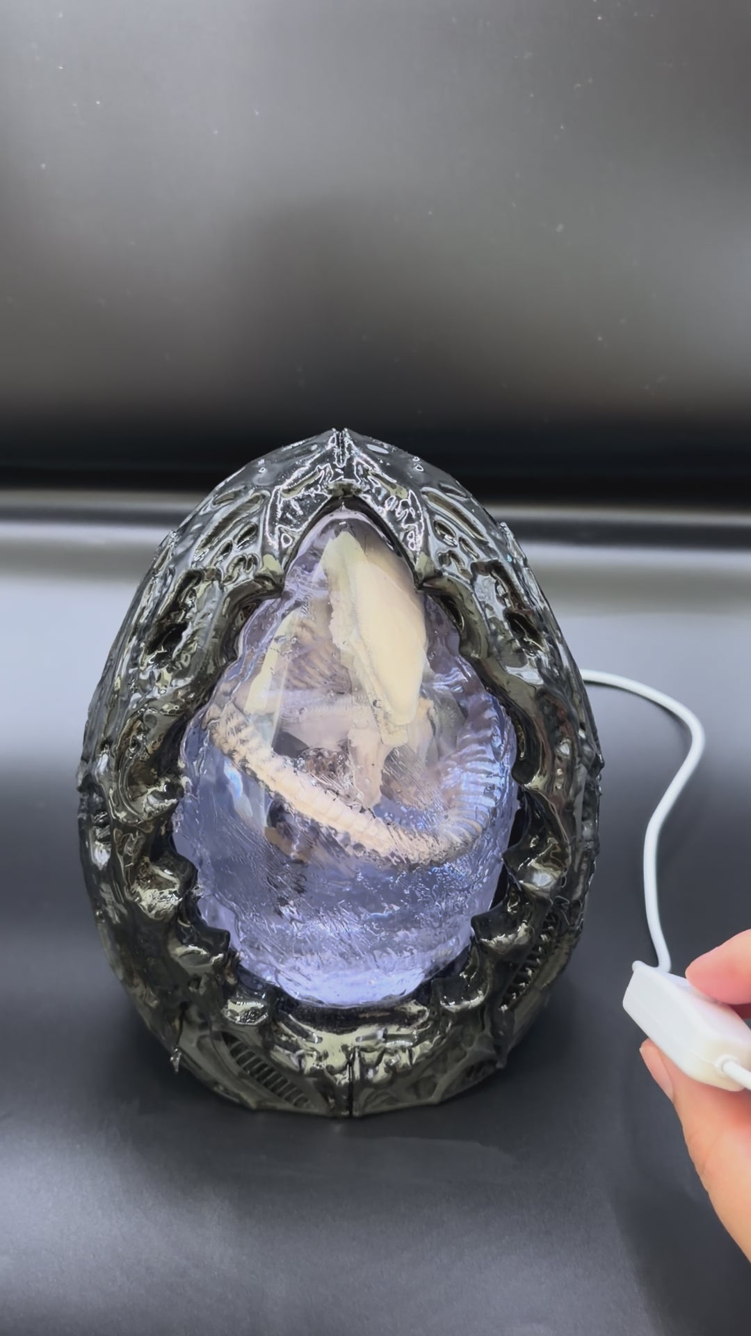 Video of the Shardlurker Specimen Night Light turning on with the push-button cable control, illuminating the translucent blue resin egg and fetal specimen inside
