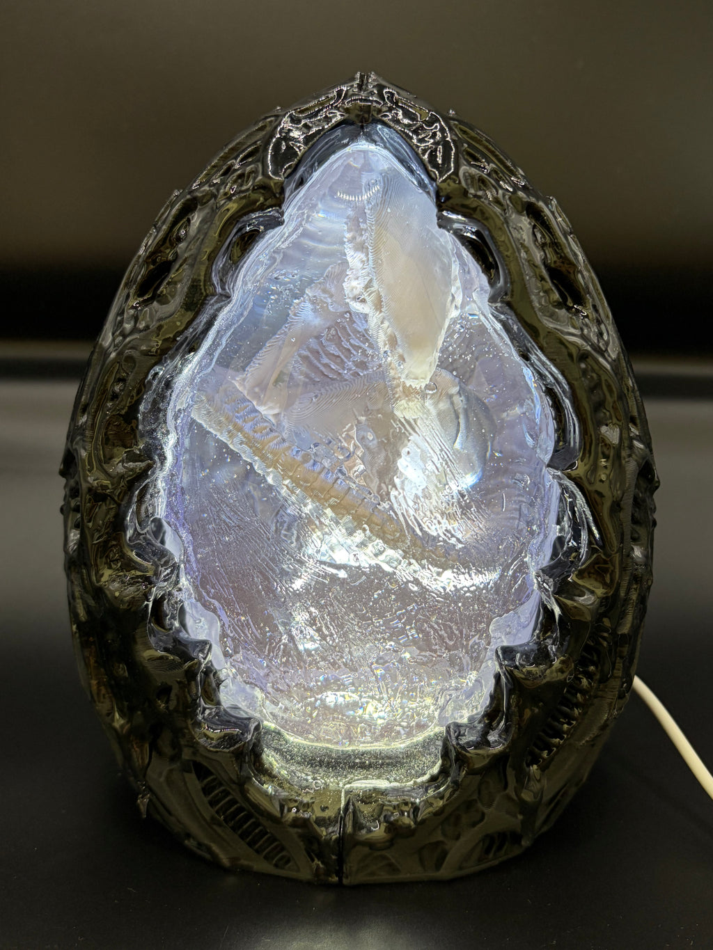 Front view of the Shardlurker Specimen Night Light with the translucent blue resin egg illuminated, revealing the fetal specimen inside