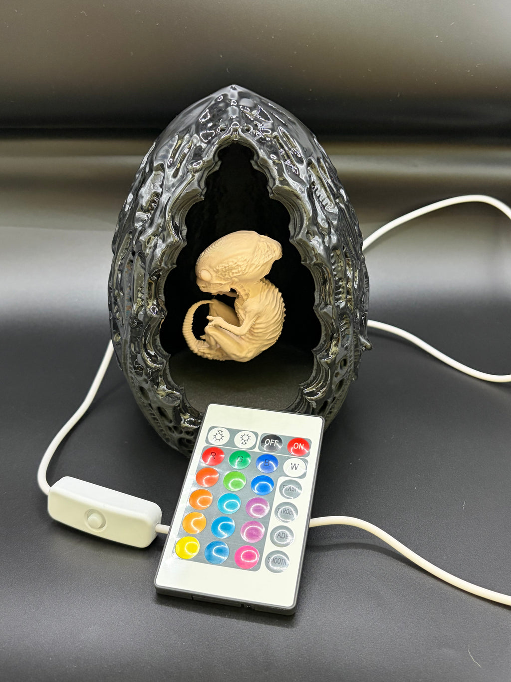 Shardlurker Specimen Night Light with glossy resin-finished containment egg, fetal specimen with dark eyes, remote control, and push-button cable control