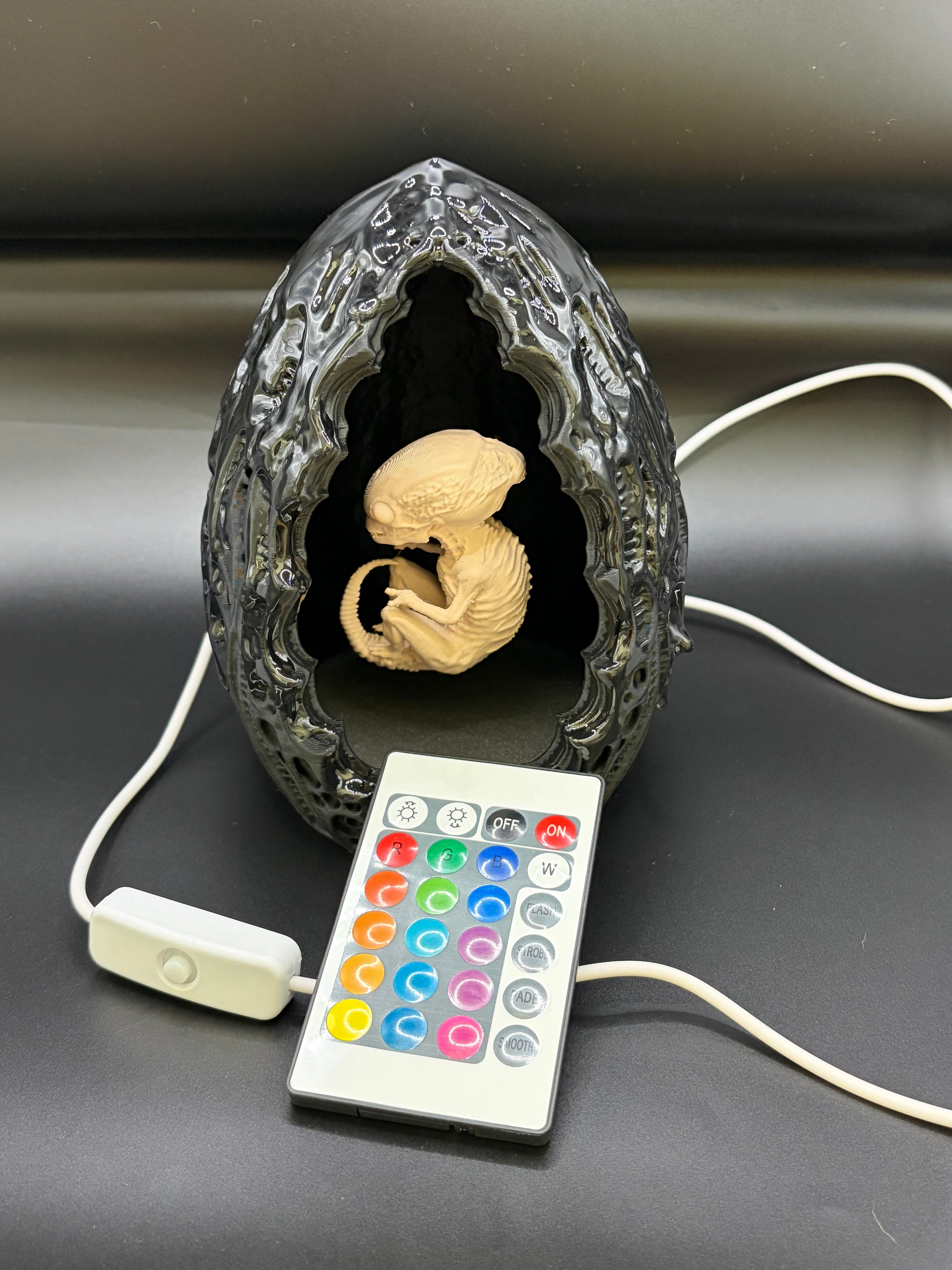 Shardlurker Specimen Night Light with glossy resin-finished containment egg, fetal specimen with dark eyes, remote control, and push-button cable control