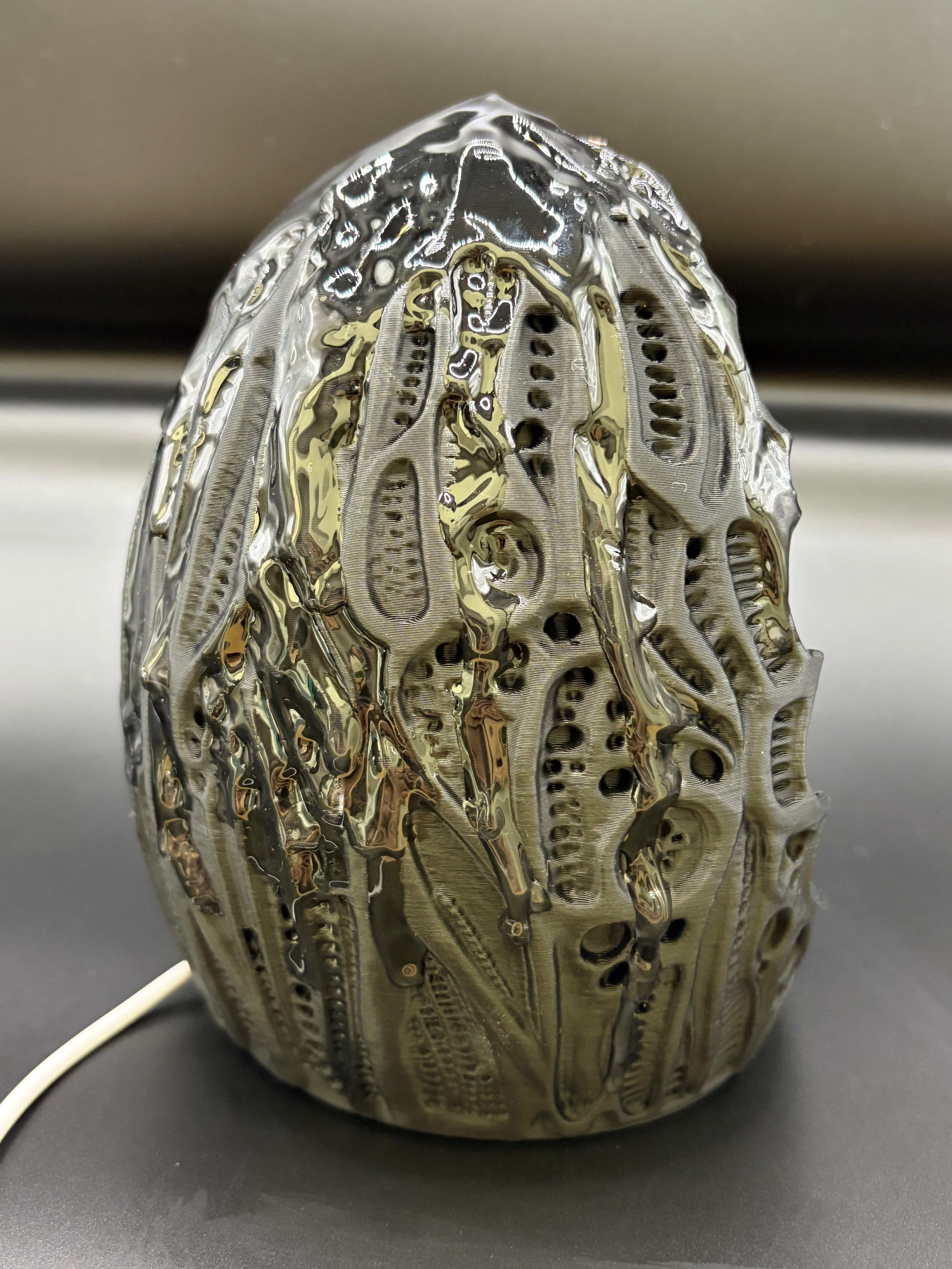 Right angled view of Shardlurker Specimen Night Light showing glossy resin-finished containment egg texture and power cable