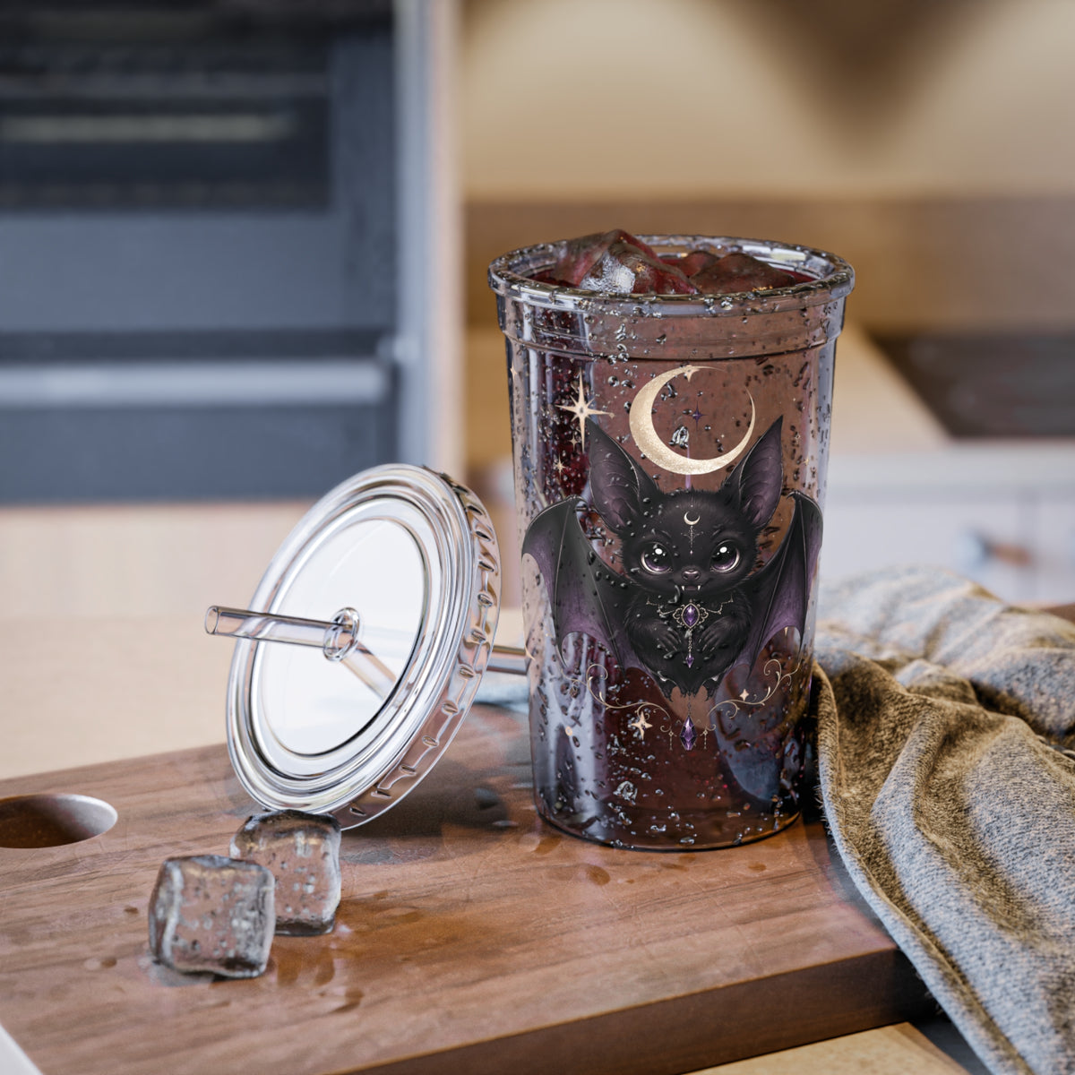 Vespertine Gothic Moon Bat 16oz acrylic tumbler filled with ice and displayed on a kitchen counter, featuring a black bat and crescent moon artwork