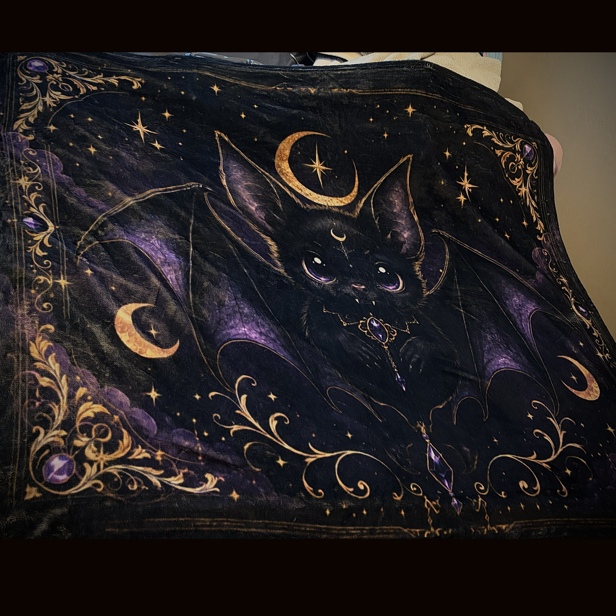 Close-up of Vespertine Gothic Moon Bat velveteen plush blanket featuring a black bat, purple wings, crescent moons, stars, and ornate gold celestial details