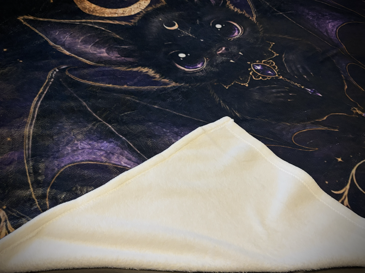 Close-up of Vespertine Gothic Moon Bat velveteen plush blanket showing printed bat artwork and soft white plush backing